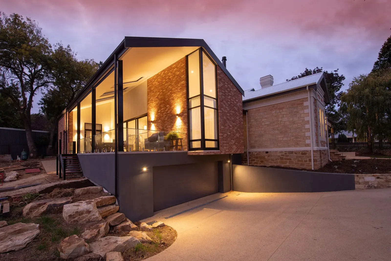 Exterior wall lights illuminate a contemporary brick home at dusk; illustrative stock photography, not Green Circuit equipment or a client installation